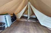 Vista interna della Tipi Tent di Camping Liefrange con letti, frigorifero e fornello in Lussemburgo.