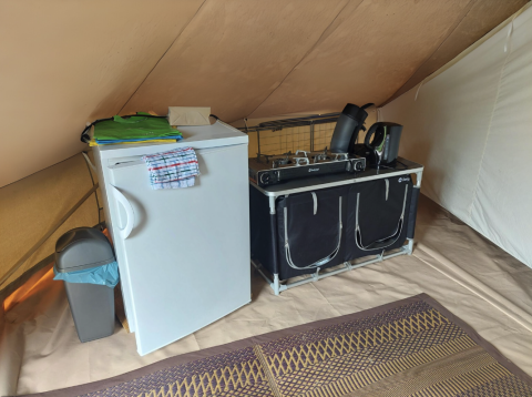 Petit coin cuisine dans une tente tipi avec réfrigérateur, gazinière et tapis au Camping Liefrange.