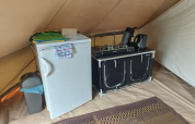 Kleine Küchenzeile in einem Tipi-Zelt mit Kühlschrank, Herd, Wasserkocher und Teppich in Camping Liefrange.
