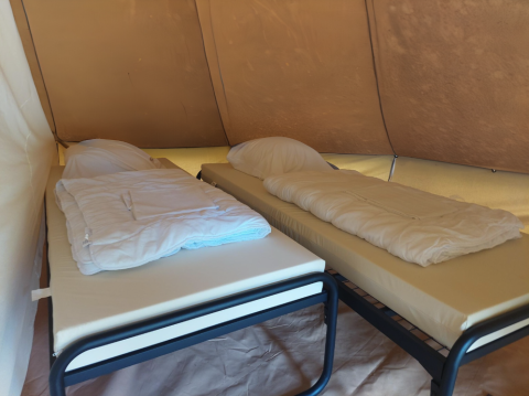 Two single beds with duvets inside a tipi tent at Camping Liefrange in Luxembourg, camping setting.