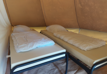 Zwei Einzelbetten mit Decken in einem Tipi-Zelt auf dem Campingplatz Liefrange in Luxemburg.