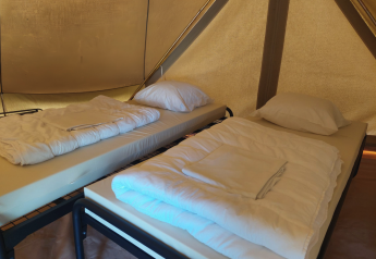 Due letti singoli con lenzuola bianche in una tenda tipi al Camping Liefrange in Lussemburgo.