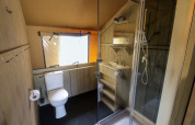 Salle de bain dans une tente safari avec WC, douche et lavabo au Camping Liefrange au Luxembourg.