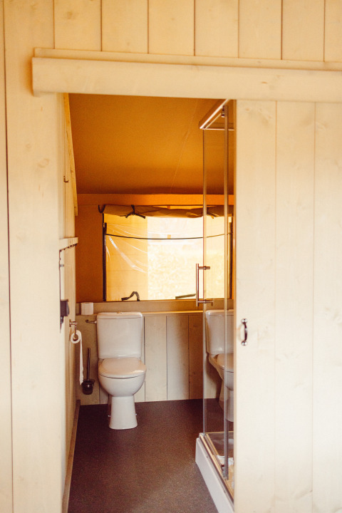 Bathroom inside a safari tent with toilet and shower at Camping Liefrange, Ranger Lodge in Luxembourg.