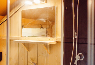 Bagno con doccia, lavabo e specchio in una tenda safari al Camping Liefrange in Lussemburgo.