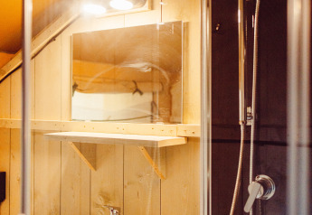 Bathroom with shower, sink, and mirror inside a safari tent lodge at Camping Liefrange in Luxembourg.