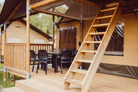 Tienda safari con terraza de madera, mesa, sillas y escalera de acceso en Camping Liefrange - Ranger Lodge.
