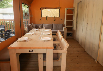 Area pranzo in tenda safari al Camping Liefrange Ranger Lodge, arredata con mobili rustici in legno.