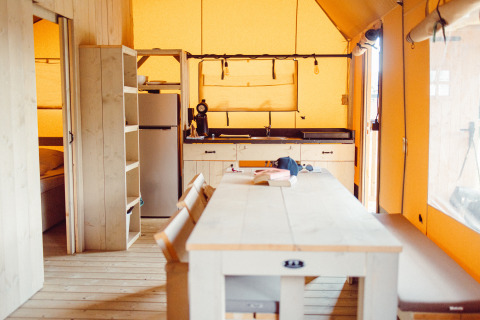 Intérieur d’une tente safari au Camping Liefrange, Ranger Lodge, Luxembourg, avec cuisine et table à manger.