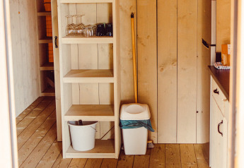 Interior view of a safari tent featuring wooden shelves, kitchenware, and a wood floor at Camping Liefrange, Luxembourg.