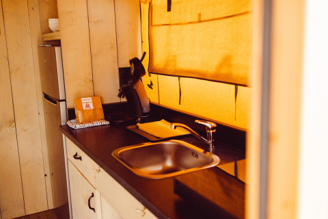 Area cucina in una tenda safari con lavandino, macchina da caffè e frigo al Camping Liefrange, Ranger Lodge.