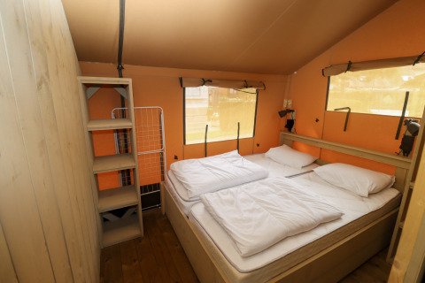 Vue intérieure d'une tente safari avec lit double et étagères au Camping Liefrange au Luxembourg.