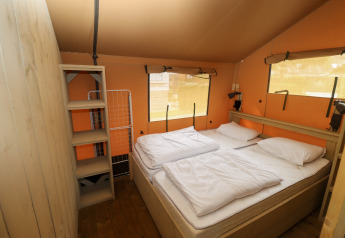 Indvendigt billede af et safari telt med dobbeltseng og hylder på Camping Liefrange i Luxembourg.
