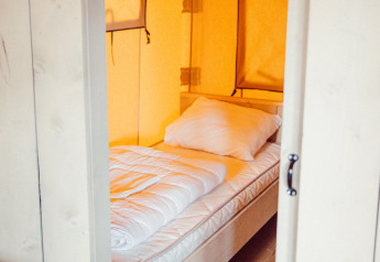 Indvendigt billede af en komfortabel seng i et safari telt på Camping Liefrange Ranger Lodge i Luxembourg.