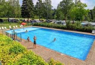 Udendørs swimmingpool med børn, liggestole og campingvogne i baggrunden i Auf Kengert, Diekirch, Luxembourg.
