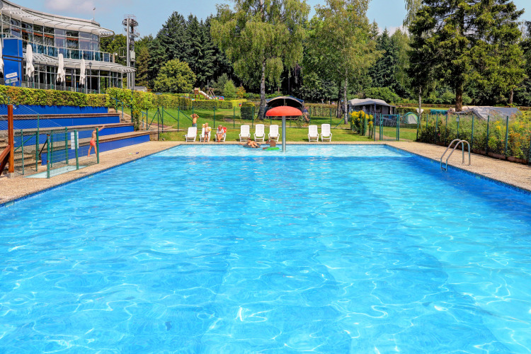 Piscina all'aperto al villaggio vacanze Auf Kengert a Diekirch, Lussemburgo, con sedie a sdraio e alberi attorno.