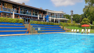 Outdoor swimming pool at a holiday park in Diekirch, Luxembourg, featuring loungers and modern buildings.