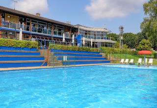 Outdoor swimming pool at a holiday park in Diekirch, Luxembourg, featuring loungers and modern buildings.
