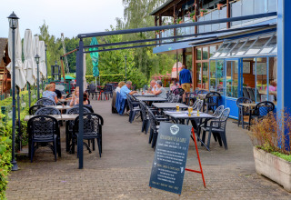 Terrasse de restaurant en plein air au parc de vacances Auf Kengert, Diekirch, Luxembourg, avec des clients.