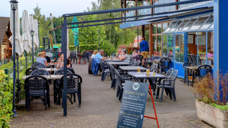 Terrazza ristorante all'aperto presso il parco vacanze Auf Kengert, Diekirch, Lussemburgo, con ospiti ai tavoli.
