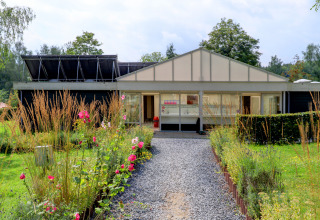 Un sendero rodeado de flores conduce a un edificio moderno en el parque de vacaciones Auf Kengert, Diekirch, Luxemburgo.
