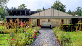 Un sentiero fiancheggiato da fiori conduce a un edificio moderno al parco vacanze Auf Kengert a Diekirch, Lussemburgo.