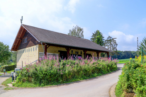Ferieparkbygning omgivet af blomster og natur ved Auf Kengert i Diekirch, Luxembourg, på en solrig dag.