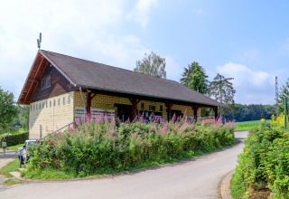 Edificio del parco vacanze ad Auf Kengert, Diekirch, Lussemburgo, circondato da fiori in una giornata di sole.