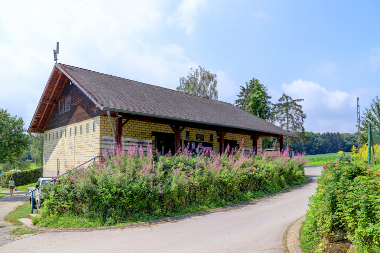 Edificio del parque de vacaciones en Auf Kengert, Diekirch, Luxemburgo, rodeado de flores en un día soleado.