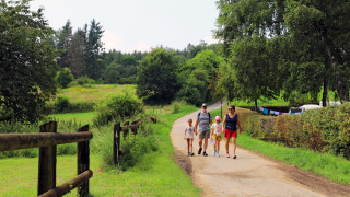 Famiglia che cammina in un sentiero panoramico ad Auf Kengert, Diekirch, immersi nel verde lussemburghese.