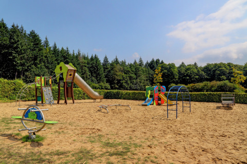 Speeltuin in vakantiepark Auf Kengert, Diekirch, Luxemburg met glijbanen, klimrekken en zandbodem.