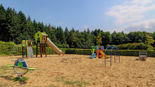Parco giochi al villaggio Auf Kengert, Diekirch, Lussemburgo, con scivoli, arrampicate e sabbia.