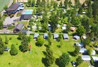 Vista aerea del villaggio turistico Auf Kengert a Diekirch, Lussemburgo, con piscina, bungalow e aree verdi.