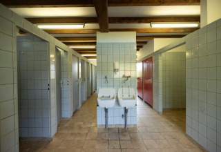 Gemeenschappelijke badkamer met douches en wastafels in Auf Kengert vakantiepark, Diekirch, Luxemburg.