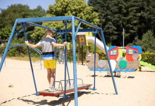 Jongen speelt op een zandige speelplaats in vakantiepark Auf Kengert in Diekirch, Luxemburg, bij zonnig weer.