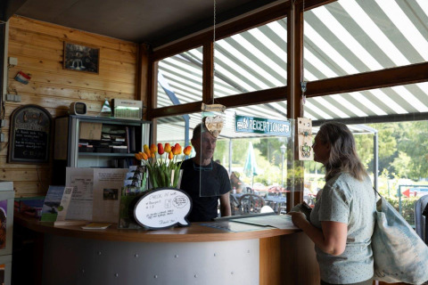 Reception at Auf Kengert holiday park in Diekirch, Luxembourg, showing a guest checking in at the counter.