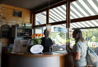 Receptie van vakantiepark Auf Kengert in Diekirch, Luxemburg, met een gast bij de balie en medewerker.