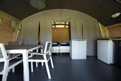 Interieur van een luxe tent op vakantiepark Auf Kengert in Diekirch, Luxemburg, met eettafel en bedden.