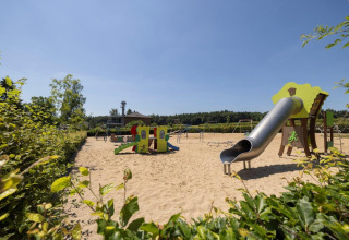 Legeplads med rutsjebane og legeredskaber i sandet ved Auf Kengert feriepark i Diekirch, Luxembourg, på en solrig dag.