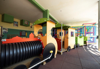 Indoor playground with colorful toy train and climbing structure at Auf Kengert holiday park, Diekirch, Luxembourg.