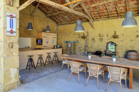 Cuisine extérieure rustique et salle à manger au Domaine La Barbe, Occitanie, France, avec mobilier en bois.