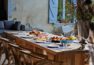 Udendørs spisebord dækket med morgenmad, frugt og croissanter på Domaine La Barbe i Occitanie, Frankrig.