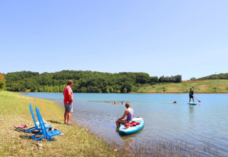 Turistas disfrutan de actividades acuáticas y relax junto al lago en Domaine La Barbe, Occitania, Francia.