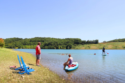 Visitors enjoy paddleboarding and relaxing by the lake at Domaine La Barbe holiday park in Occitanie.
