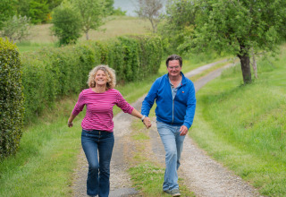 Pareja camina cogida de la mano por un sendero en Domaine La Barbe, Occitania, Francia, rodeada de naturaleza.