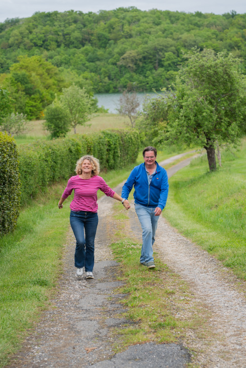 Paar spaziert Hand in Hand auf einem Weg im Domaine La Barbe, Occitanie, Frankreich, von Grün umgeben.