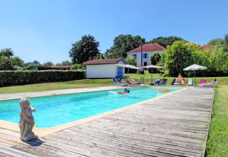 Buitenzwembad aan Domaine La Barbe vakantiepark in Occitanië, Frankrijk, met ligstoelen en huizen op de achtergrond.