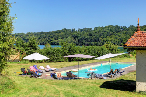 Udendørs swimmingpool med liggestole, parasoller og udsigt over grønne træer ved Domaine La Barbe, Occitanie.