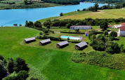 Vista aerea del parco vacanze Domaine La Barbe in Occitania, Francia, con prati verdi, piscina e lago.
