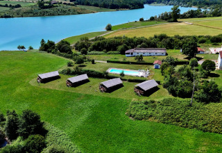 Luftfoto af Domaine La Barbe feriepark i Occitanie, Frankrig, med grønne marker, pool og sø.